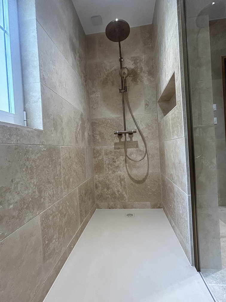 Douche à l'italienne avec robinetterie noire dans une salle de bain rénovée