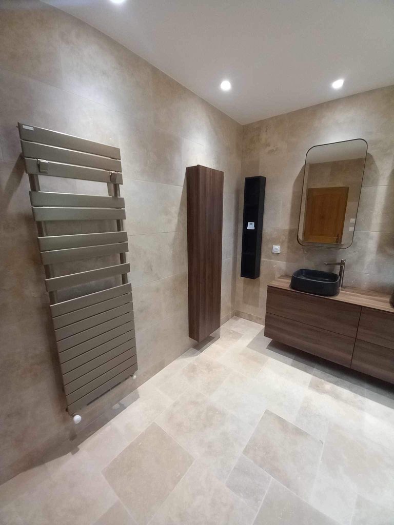 Vue d'ensemble d'une salle de bain rénovée avec meuble vasque en bois et sèche-serviettes