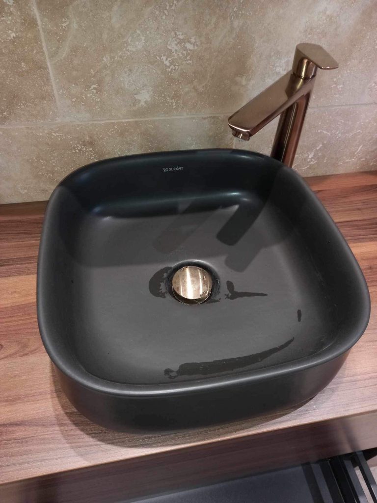 Vasque noire à poser sur meuble en bois dans une salle de bain moderne