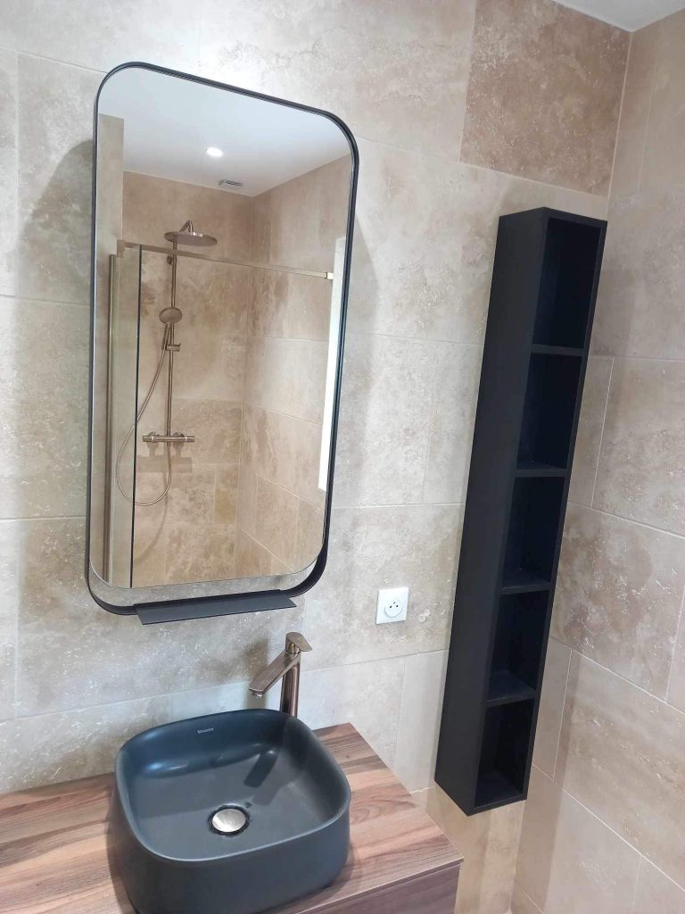 Miroir avec angles arrondis au-dessus d'un meuble vasque dans une salle de bain rénovée