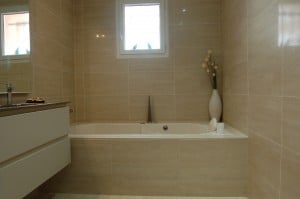 Baignoire balnéo installée sous deux fenêtres dans une salle de bain lumineuse.