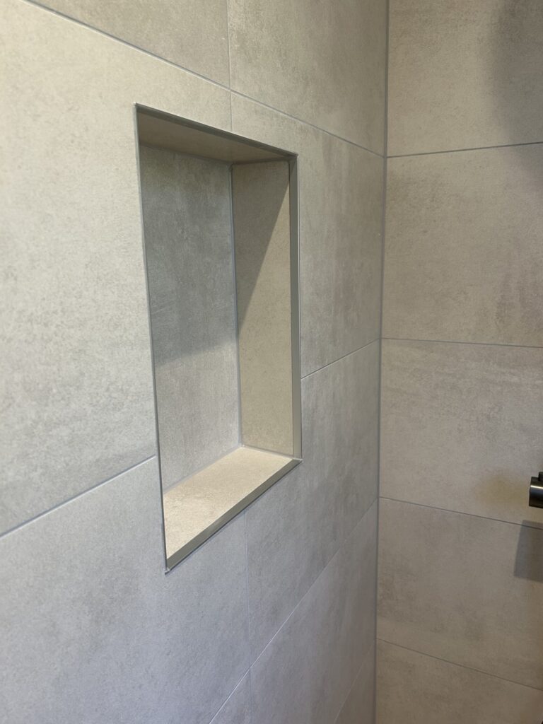 Niche de rangement intégrée dans une douche à l'italienne lors d'une rénovation de salle de bain