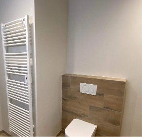 WC suspendu avec habillage bois et sèche-serviettes dans une salle de bain rénovée à Montélimar