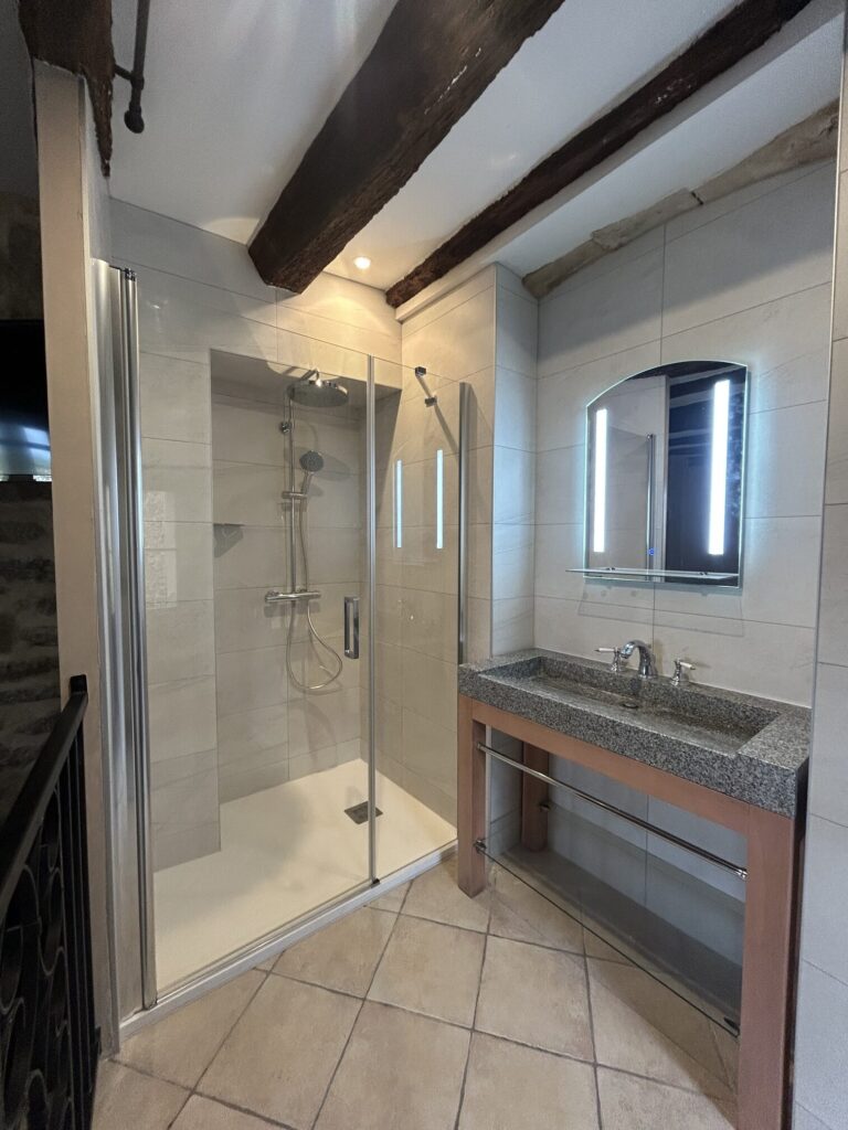 Vue d'ensemble d'une salle de bain d'hôtel rénovée à Grignan avec douche à l'italienne et meuble vasque.