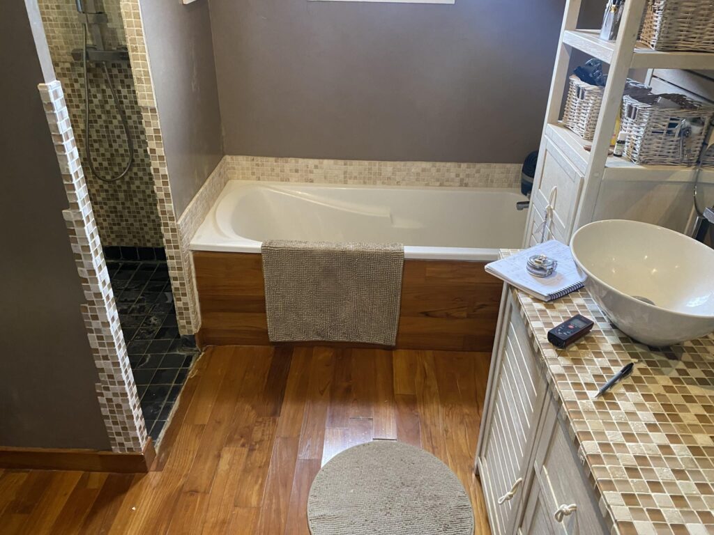 Vue d'ensemble d'une salle de bain rénovée avec douche, meuble vasque et revêtement imitation bois à Montélimar