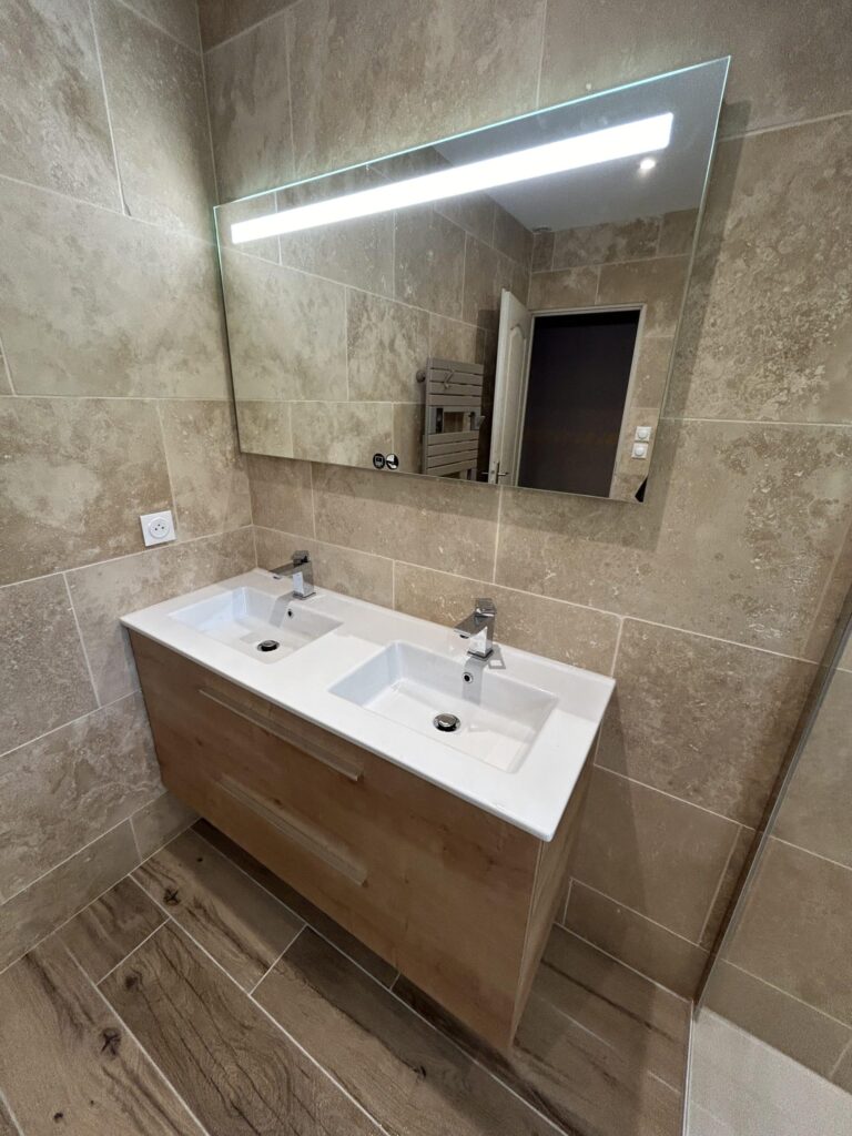 Double vasque avec grand miroir rétroéclairé LED dans une salle de bain rénovée