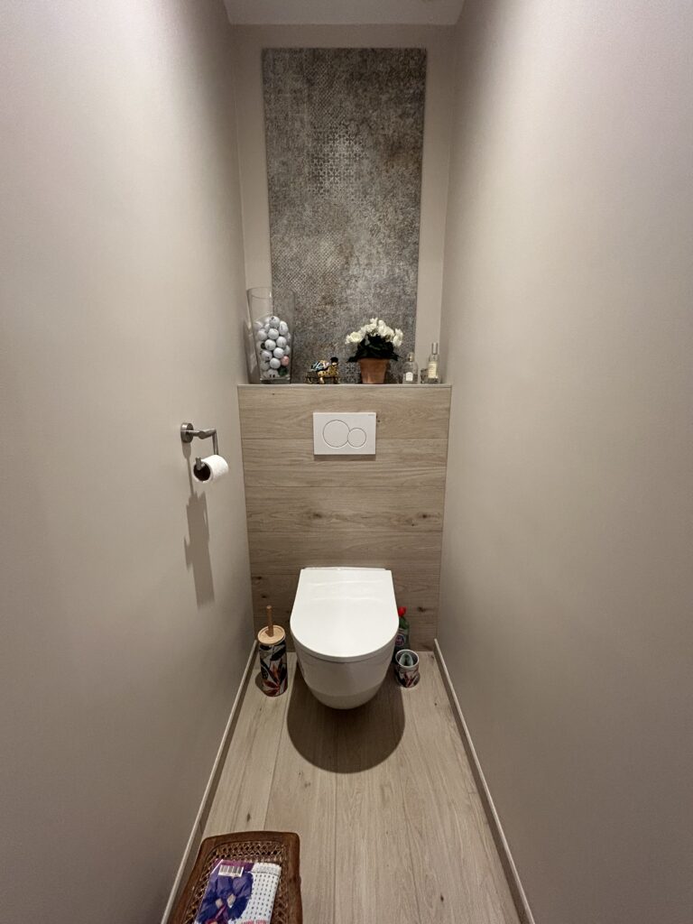Toilettes rénovées avec WC suspendu et habillage mural effet bois