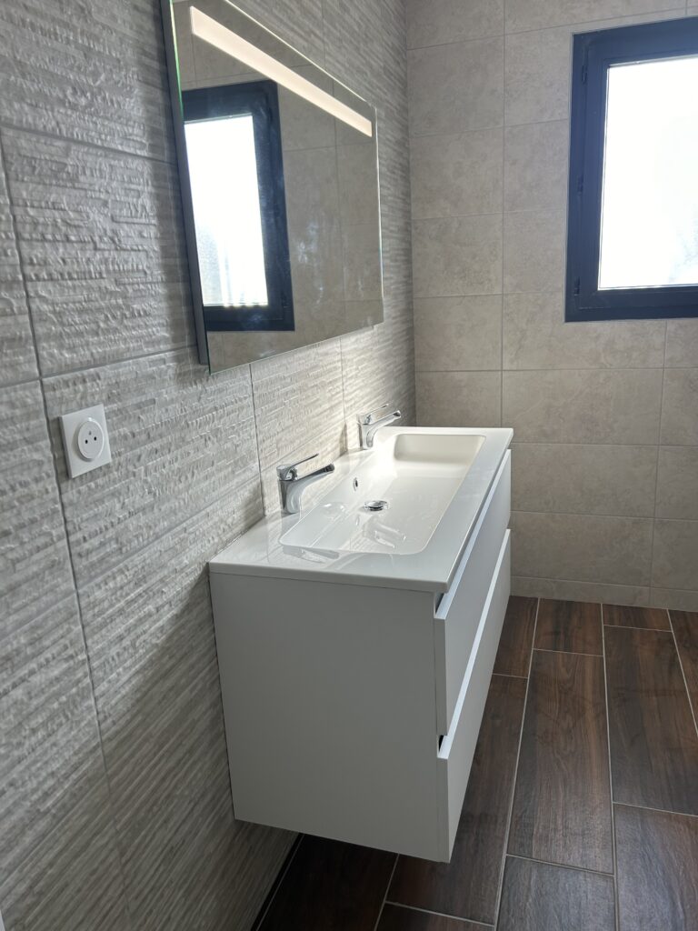 Meuble double vasque suspendu avec miroir LED dans une salle de bain rénovée.