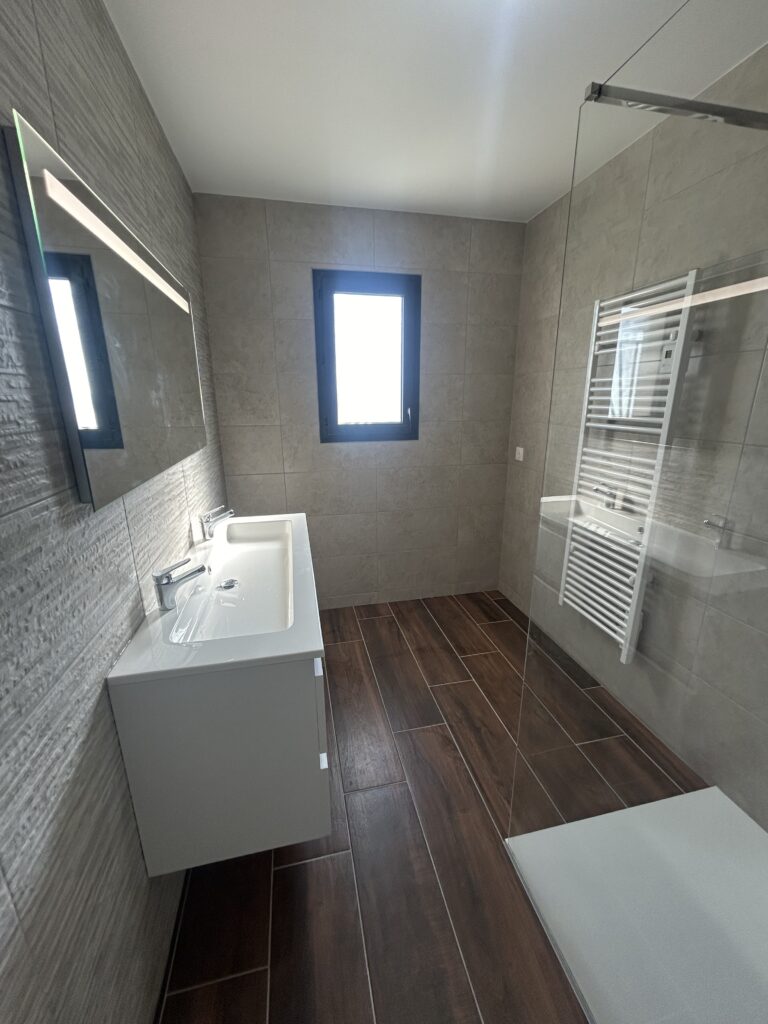 Salle de bain rénovée avec meuble double vasque suspendu et douche à l'italienne.