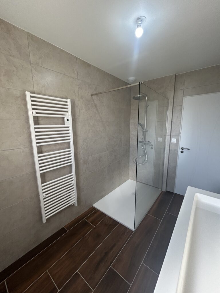 Vue d'ensemble d'une salle de bain rénovée avec douche à l'italienne et double vasque.
