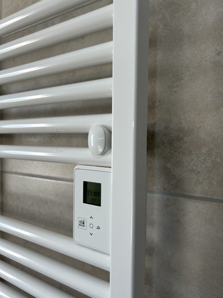 Sèche-serviettes électrique blanc installé dans une salle de bain rénovée après un dégât des eaux.