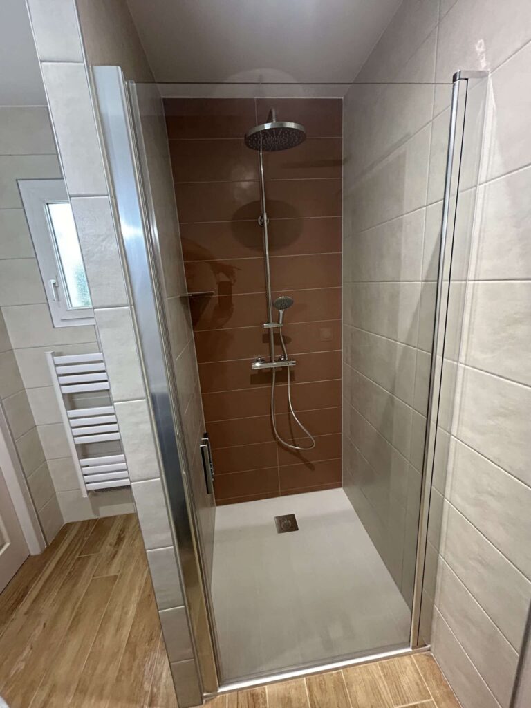 Salle de bain rénovée avec douche à l'italienne, meuble vasque suspendu et carrelage grand format.
