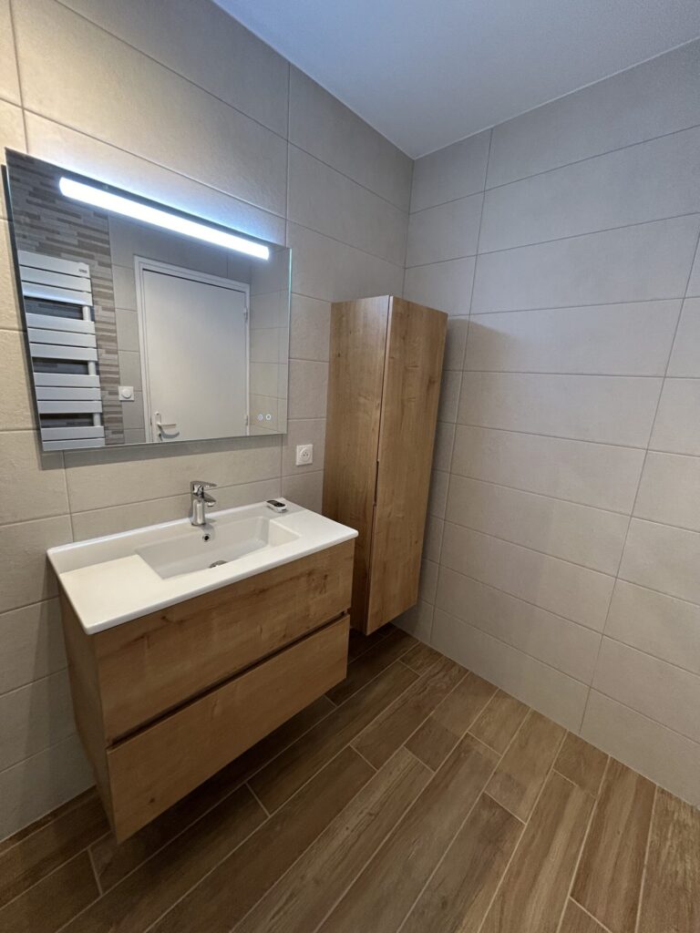 Vasque moderne avec miroir éclairé dans une salle de bain rénovée.
