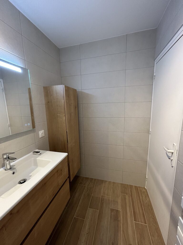 Meuble vasque suspendu avec plan vasque blanc installé lors d'une rénovation de salle de bain.