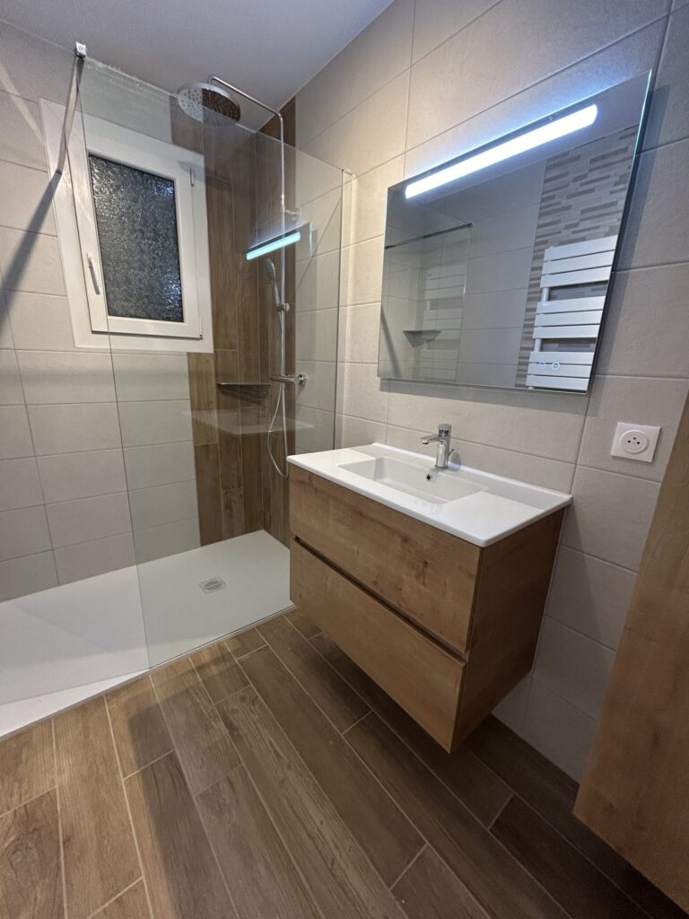 Vue d'ensemble d'une salle de bain rénovée avec meuble vasque suspendu par Drôme Rénovation.