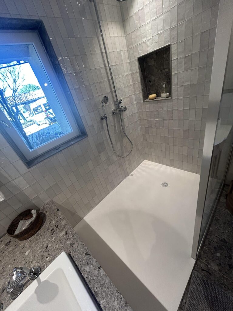 Faïence effet zellige et fenêtre apportant de la lumière naturelle dans une douche à l'italienne rénovée à Salette.