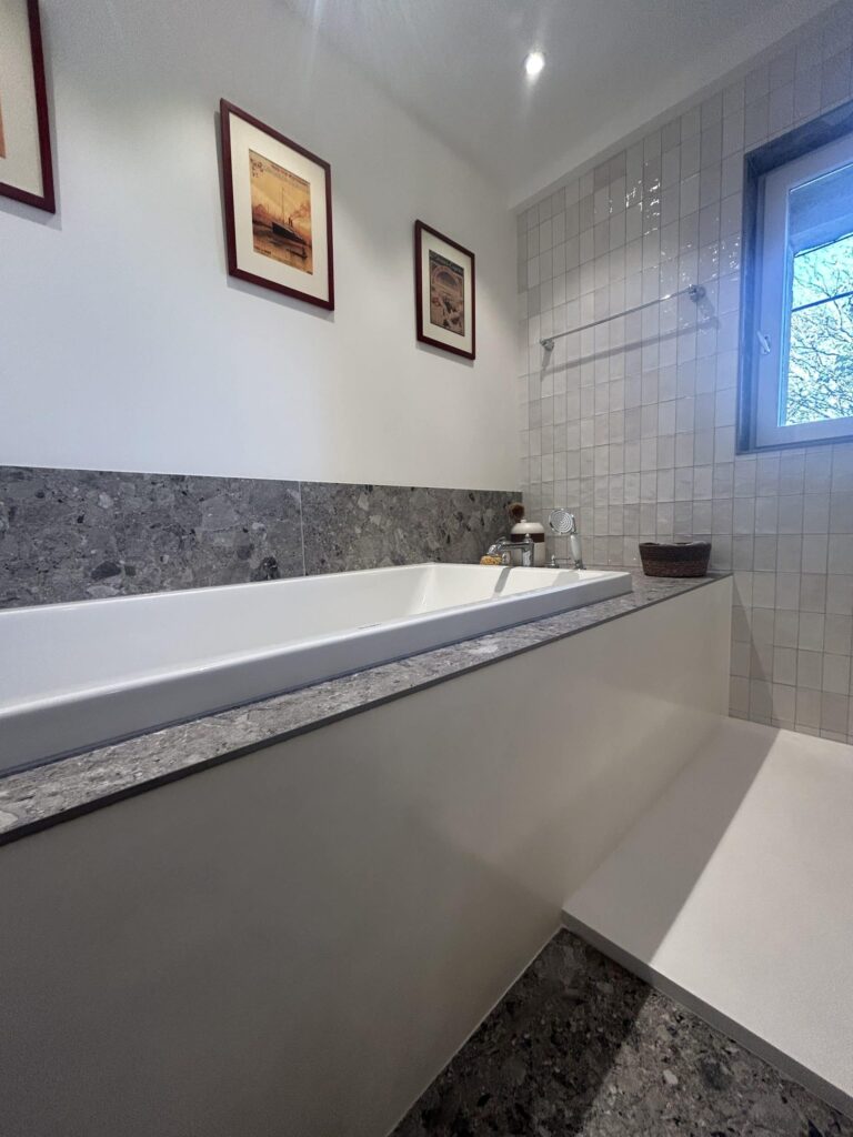 Habillage de baignoire avec revêtement effet terrazzo dans une salle de bain rénovée à Salette.