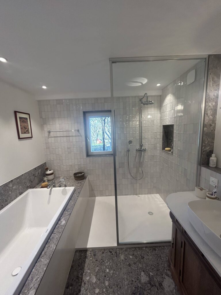 Paroi de douche vitrée sur mesure installée dans une salle de bain rénovée à Salette.