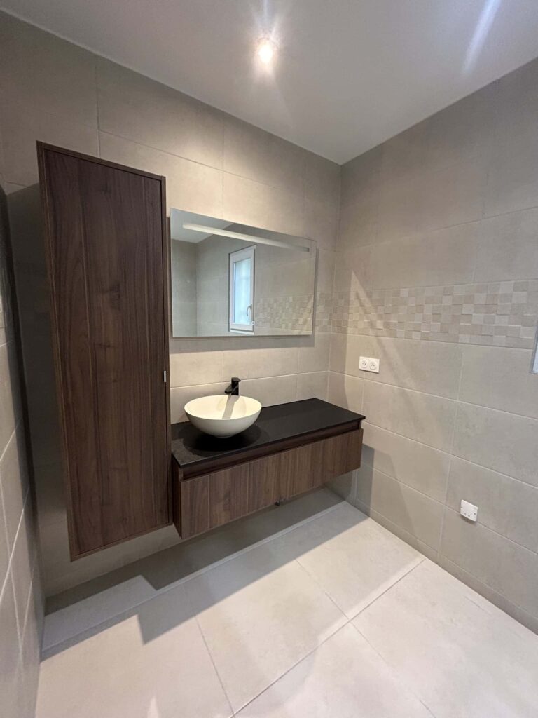 Meuble vasque suspendu avec plan noir et miroir dans une salle de bain rénovée à Cléon-d'Andran.