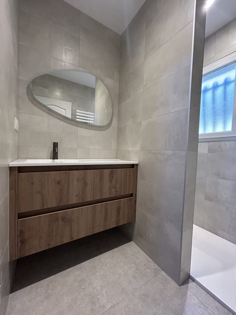 Vue du meuble suspendu et de la douche à l'italienne dans une salle de bain rénovée